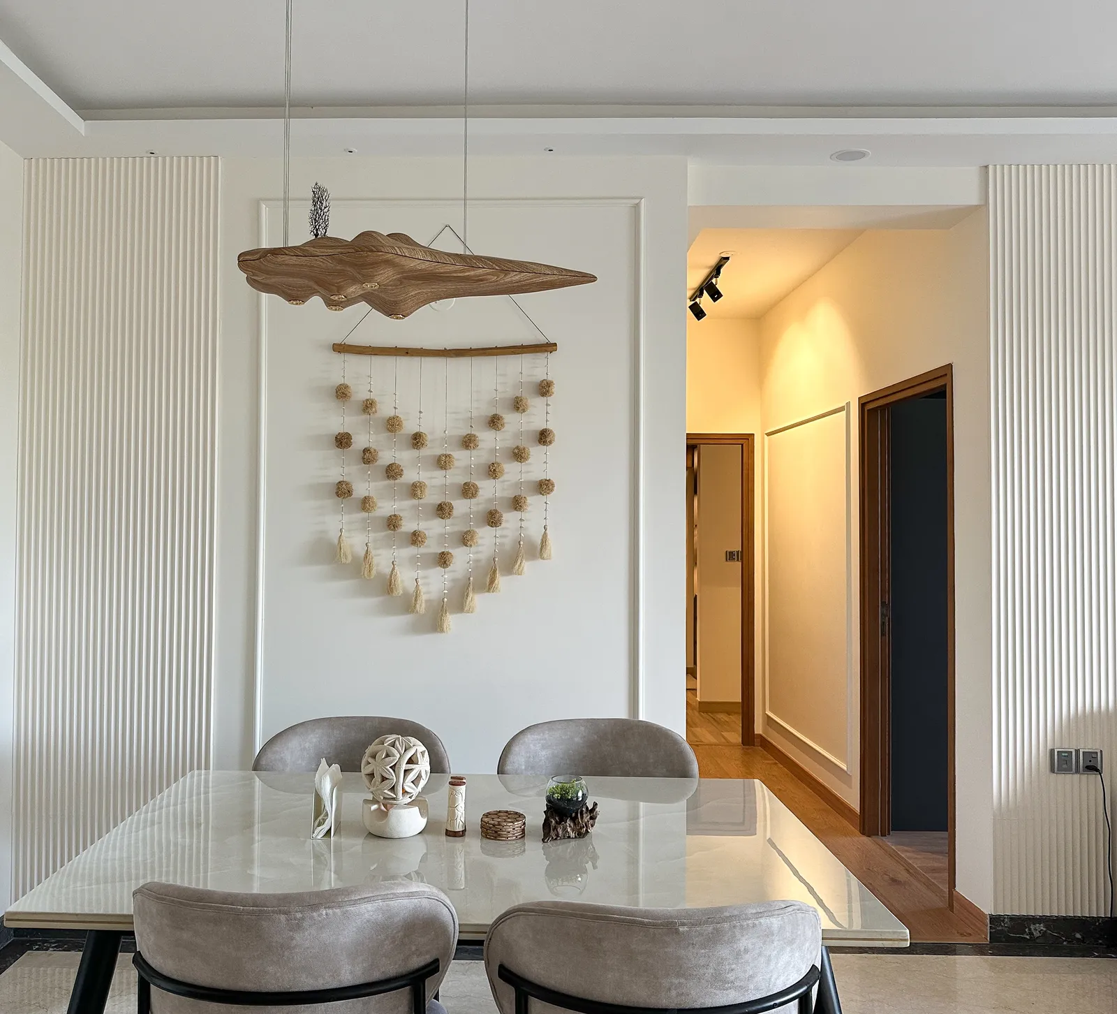 Dining area with macramé wall art and view into the corridor — Somani's Residence